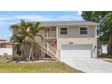 Charming two-story home featuring a two-car garage, front yard with palms, and staircase to the front door at 921 Lynnlea Ln, Tarpon Springs, FL 34689