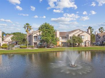 Waterfront condo building with mature landscaping, fountain view, and a blue sky with scattered clouds at 10442 Villa View Cir, Tampa, FL 33647
