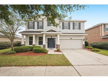 Charming two-story home with a well-manicured lawn, mature tree, and a two-car garage and inviting entrance at 12402 Fairlawn Dr, Riverview, FL 33579