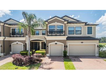 Beautiful townhome exterior with a two-car garage, lush landscaping, and a well-maintained brick driveway at 18860 Beautyberry Ct, Lutz, FL 33558