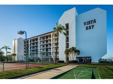 Vista Bay condo building featuring a tennis court, shuffleboard and lush landscaping on a beautiful sunny day at 19111 Vista Bay Dr # 304, Indian Shores, FL 33785