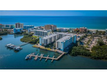 Stunning aerial view of a beachfront condo complex with boat docks and ocean views in a tropical setting at 19531 Gulf Blvd # 205, Indian Shores, FL 33785