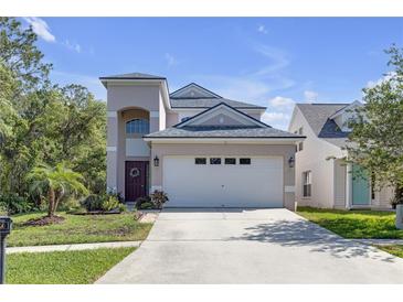 Two-story home with neutral paint, a two car garage, and tidy front yard with palm trees under a beautiful blue sky at 5634 Tanagergrove Way, Lithia, FL 33547