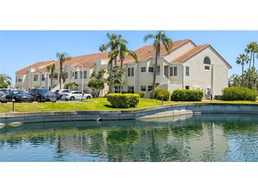 Well-maintained building exterior with lush landscaping, palm trees, pond and parking at 6131 Bahia Del Mar Blvd # 240, St Petersburg, FL 33715