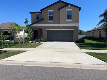 Inviting two-story home with a neutral color scheme, gray garage door, and extended driveway on a sunny day at 1038 Ocean Spray Dr, Ruskin, FL 33570
