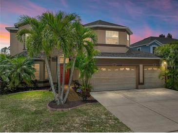 Two-story home features a three-car garage, and lush landscaping with several palm trees at 11308 Callaway Pond Dr, Riverview, FL 33579