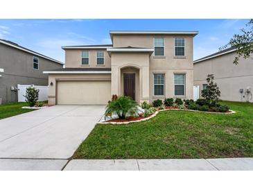 Two-story home featuring neutral color scheme, attached garage, and well-maintained landscaping at 12017 Grand Kempston Dr, Gibsonton, FL 33534