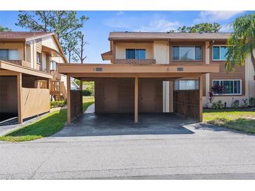 Cozy townhouse with covered parking, showing unit numbers 4424 and 4420 under a bright blue sky at 4424 Pelorus Dr, New Port Richey, FL 34652