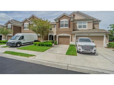 Exterior view of a two-story townhome with attached garages, landscaped yard, and vehicles in the driveway at 4603 Barnstead Dr, Riverview, FL 33578
