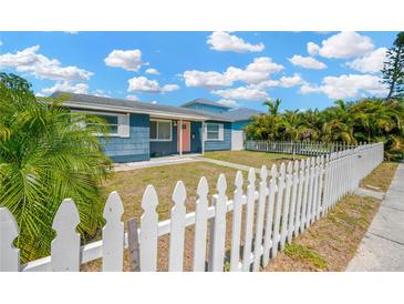 Charming blue home featuring a well-manicured lawn and classic white picket fence at 5367 5Th N Ave, St Petersburg, FL 33710