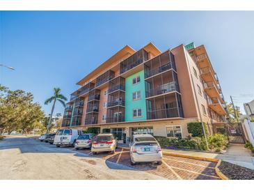 Condominium building with a colorful exterior and screened-in balconies above a parking area on a sunny day at 750 Burlington N Ave # 4L, St Petersburg, FL 33701