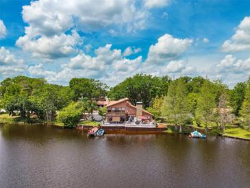 Waterfront home with private dock, serene lake views, and lush landscaping creating a peaceful oasis at 17301 Estes Rd, Lutz, FL 33548