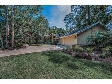 Sprawling single Gathering home featuring lush landscaping, brick driveway, and a 2-car garage at 20 Willowwood Ln, Oldsmar, FL 34677