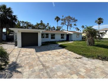 Charming single-story home with a beautifully paved driveway and lush tropical landscaping under a clear, sunny sky at 204 162Nd Ave, Redington Beach, FL 33708