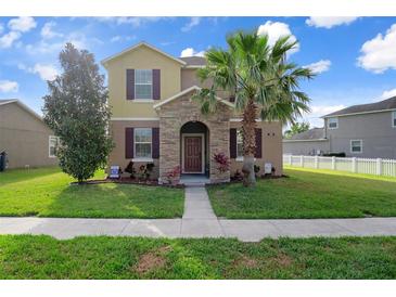 Charming two-story home with a well-manicured lawn, a stone-accented entry, and lush landscaping at 21046 Passive Porch Dr, Land O Lakes, FL 34637