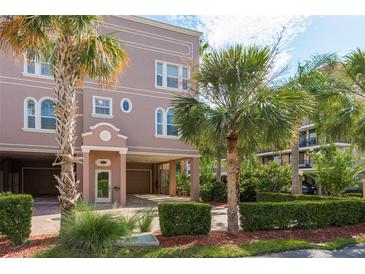 Multi-story home exterior with palm trees, manicured landscaping, and covered parking at 600 Reserve Ln, Dunedin, FL 34698