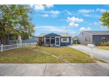 Charming single-story blue home featuring a screened-in porch and a well-maintained front yard at 940 57Th N Ave, St Petersburg, FL 33703