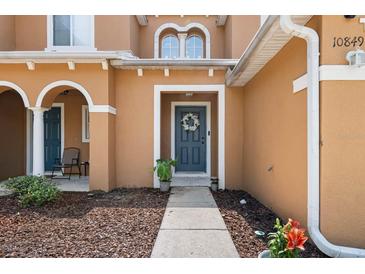 Charming home featuring a welcoming front door with a decorative wreath and covered porch with seating area at 10849 Kensington Park Ave, Riverview, FL 33578
