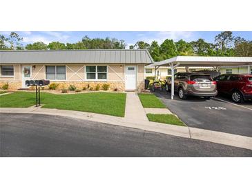 Charming condo exterior with stone accents, lush lawn, covered parking, and well-maintained landscaping at 11728 Carissa Ln # 0, New Port Richey, FL 34654