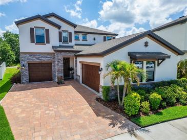 Charming two-story home featuring a lush landscaped yard and brick-paved driveway at 13042 Pennybrook Dr, Riverview, FL 33579