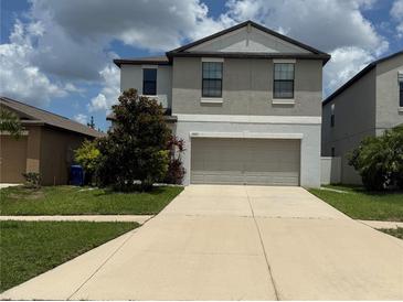 Inviting two-story home with a well-maintained lawn, concrete driveway, and attached garage at 13923 Arbor Pines Dr, Riverview, FL 33579