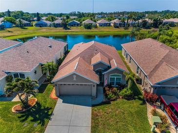 A serene aerial view showcases a beautiful home with lush landscaping and a tranquil lake backdrop at 2344 Pleasant Hill Ln, Holiday, FL 34691