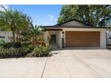 Charming home featuring a well-manicured lawn, beautiful landscaping, and a spacious two-car garage at 1509 Coachlight Way, Dunedin, FL 34698