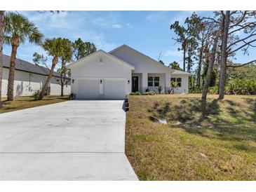 Charming one-story home boasts a manicured lawn, a two-car garage and a modern exterior at 2444 Jacobs St, Port Charlotte, FL 33953