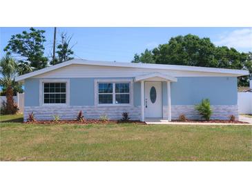 Charming single-story home featuring a light blue exterior, decorative stone accents, and a well-manicured lawn at 5143 Jasmine Cir, St Petersburg, FL 33714