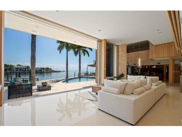 Bright living room with tile floors that opens to an outdoor pool and waterfront views at 10 Brightwaters Ne Cir, St Petersburg, FL 33704