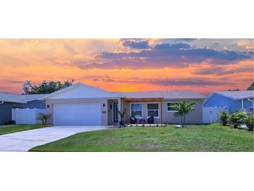Charming single-Gathering home with a well-manicured lawn and cozy front porch seating area under a beautiful sunset sky at 10884 118Th St, Seminole, FL 33778