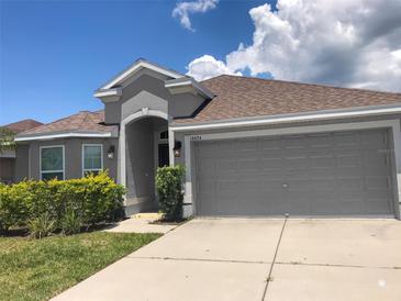 Charming single-story home featuring a two-car garage, well-maintained landscaping, and a welcoming entrance at 14434 Scottburgh Glen Dr, Wimauma, FL 33598