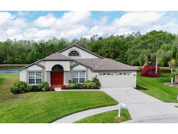 Charming single-story home featuring a manicured lawn, red front door, and attached two-car garage at 5331 Villagebrook Dr, Wesley Chapel, FL 33544
