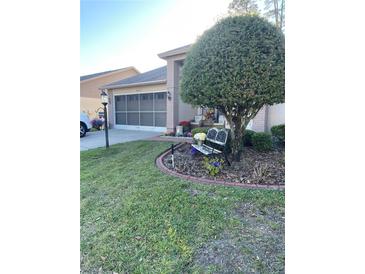 Charming home featuring a well-manicured lawn and decorative flower garden with a bench under a mature shade tree at 18607 Bent Pine Dr, Hudson, FL 34667