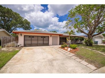 Charming single-story home featuring a well-kept lawn, mature trees and a two-car garage at 1874 Cameo Way, Clearwater, FL 33756