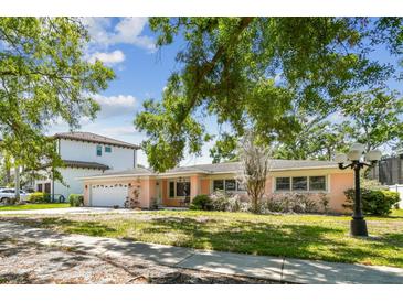 Charming single-story home with a well-maintained lawn and mature trees, set against a blue sky at 2607 S Bryant Cir, Tampa, FL 33629
