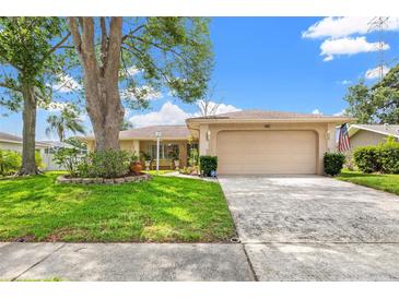 Charming single-story home featuring a well-manicured lawn, mature tree, and two-car garage at 3360 Masters Dr, Clearwater, FL 33761