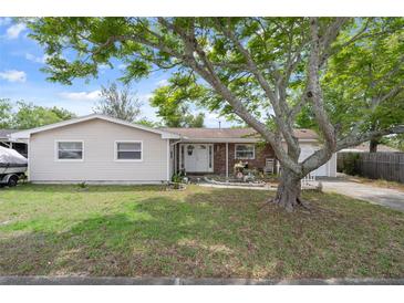 Inviting single-Gathering home with a well-manicured front lawn, mature shade trees, and a cozy, welcoming entrance at 9414 Northcliffe Blvd, Spring Hill, FL 34606