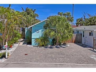 Charming blue home with lush tropical landscaping and a brick paver driveway at 13123 4Th E St, Madeira Beach, FL 33708