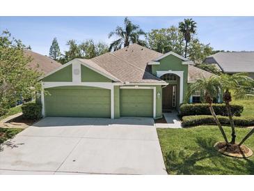 Charming single-story home featuring a well-manicured lawn, mature trees, and a three-car garage at 1211 Penny Ct, Dunedin, FL 34698