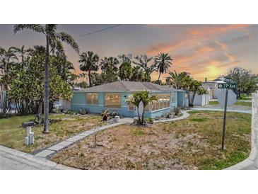 Charming light blue home featuring tropical landscaping and a welcoming pathway under a stunning colorful sunset sky at 512 79Th Ave, St Pete Beach, FL 33706