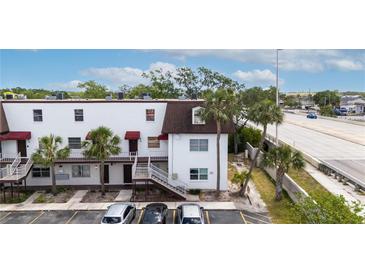 White two-story building with brown accents and palm trees in front of the parking lot at 9001 Tudor Dr # H210, Tampa, FL 33615