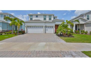 Beautiful two-story home with a brick driveway, three-car garage, and lush landscaping at 933 Signet Dr, Apollo Beach, FL 33572