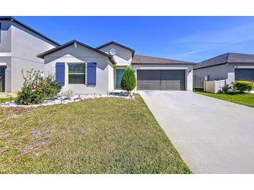 Charming single-story home with a well-manicured lawn, colorful flowerbed, and a two-car garage at 9433 Channing Hill Dr, Sun City Center, FL 33573