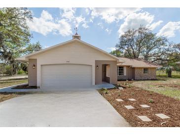 Charming one-story home with a two-car garage, light brick accents, and a well-manicured front yard at 11480 Genter Dr, Spring Hill, FL 34609