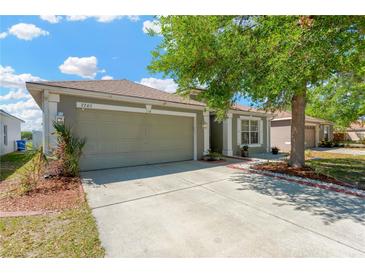 Charming home featuring a two-car garage, neutral color scheme, and front yard landscaping at 7705 Dragon Fly Loop, Gibsonton, FL 33534
