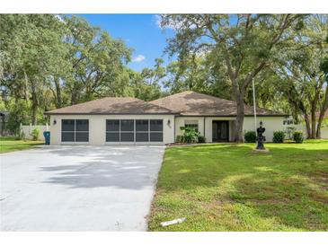 Charming single-story home featuring a well-manicured lawn, double garage, and beautiful mature shade trees at 9395 Belvedere St, Spring Hill, FL 34608