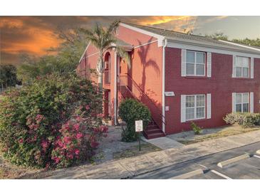 Charming brick condo with a private entry, lush landscaping, stairs leading to the second level, and an orange sky at sunset at 1095 82Nd N Ter # 1095A, St Petersburg, FL 33702