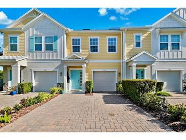 Charming multi-story townhomes featuring colorful exteriors, attached garages, and a welcoming paver driveway at 1103 Coral Ln, Dunedin, FL 34698