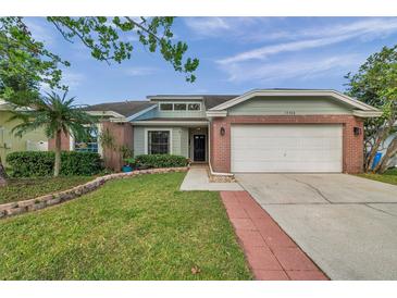 Charming single-story home featuring a well-manicured lawn, brick accents, and an attached two-car garage at 13308 Kearney Way, Tampa, FL 33626